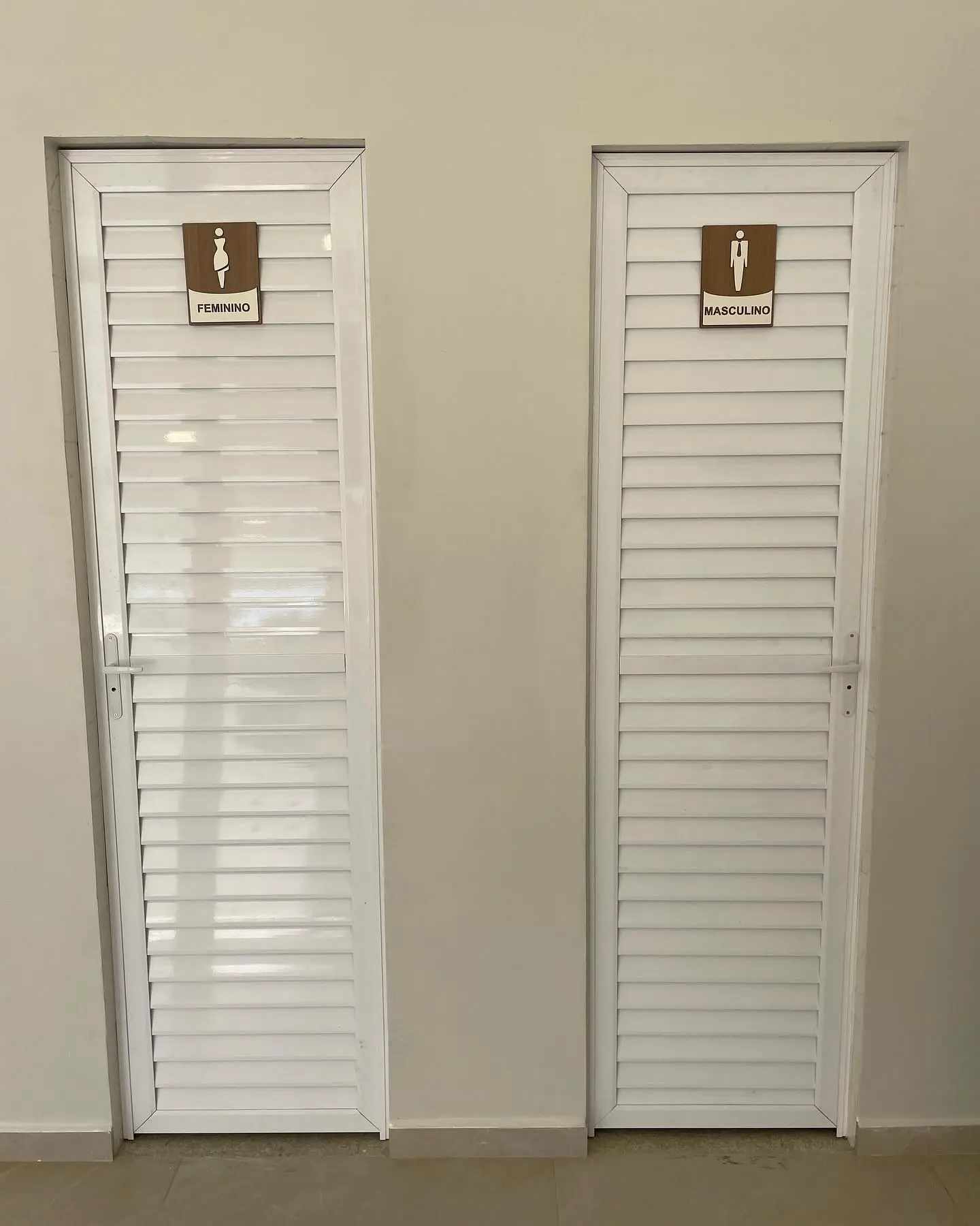 Portas brancas com placas de identificação dos banheiros