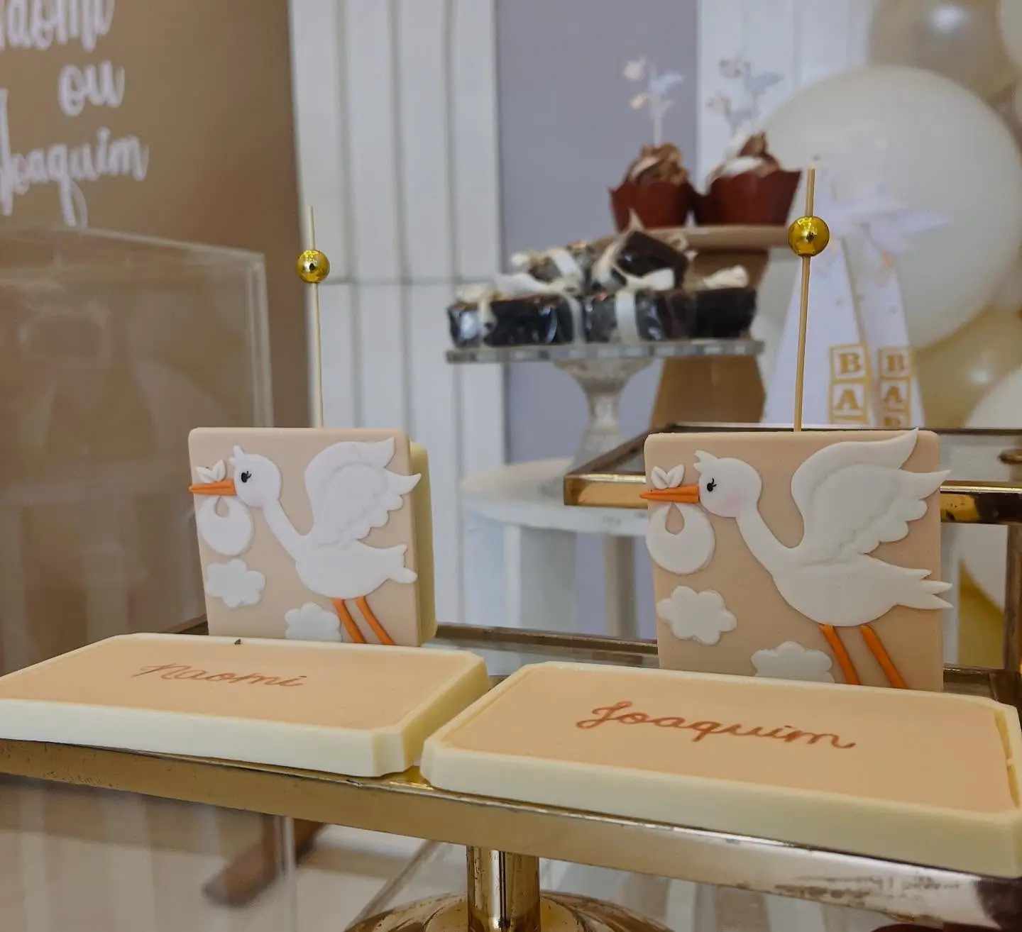 Doces de chá de bebê decorados com figuras de cegonhas e a inscrição Joaquim