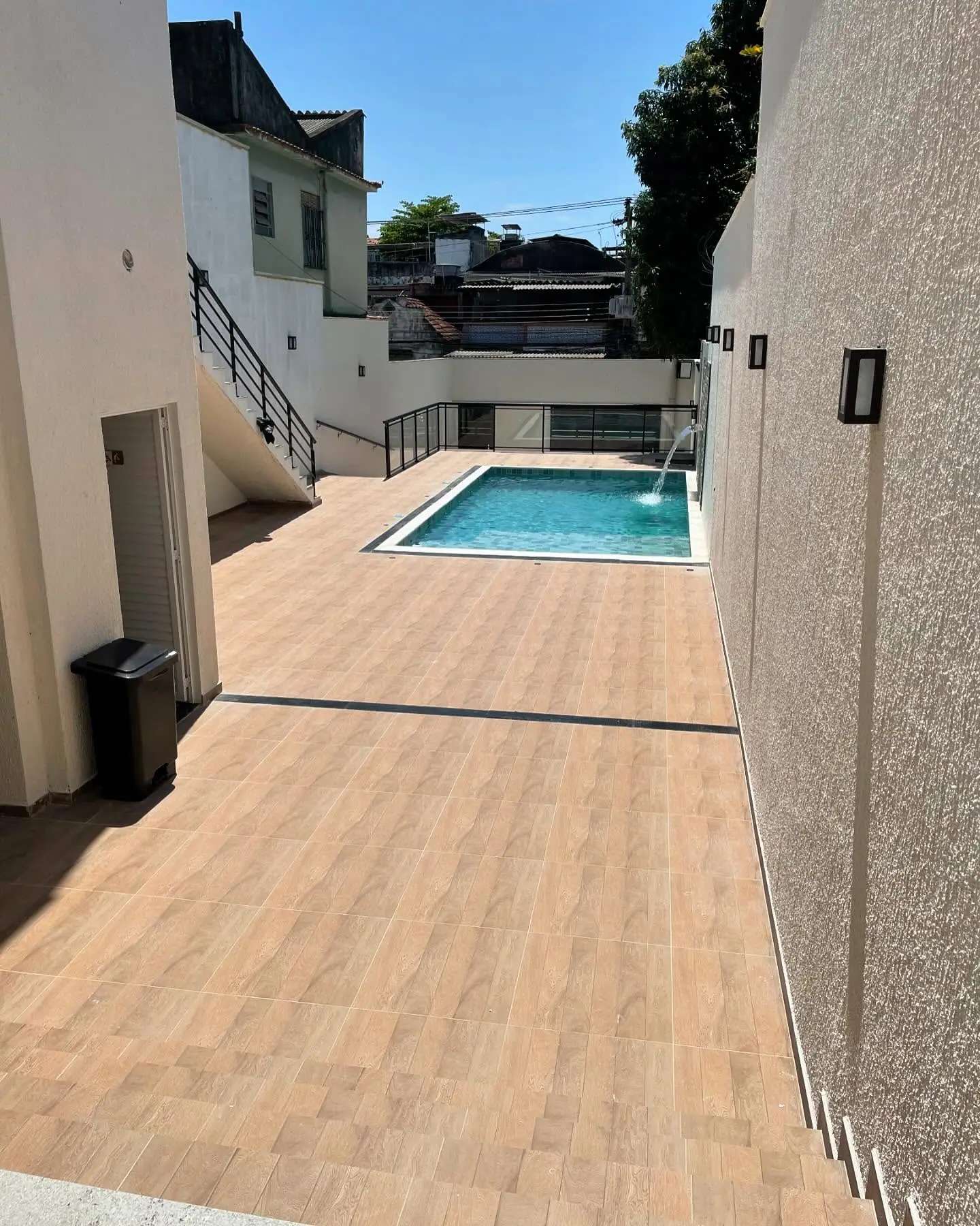 Passagem externa com piso de aspecto amadeirado voltada para a piscina