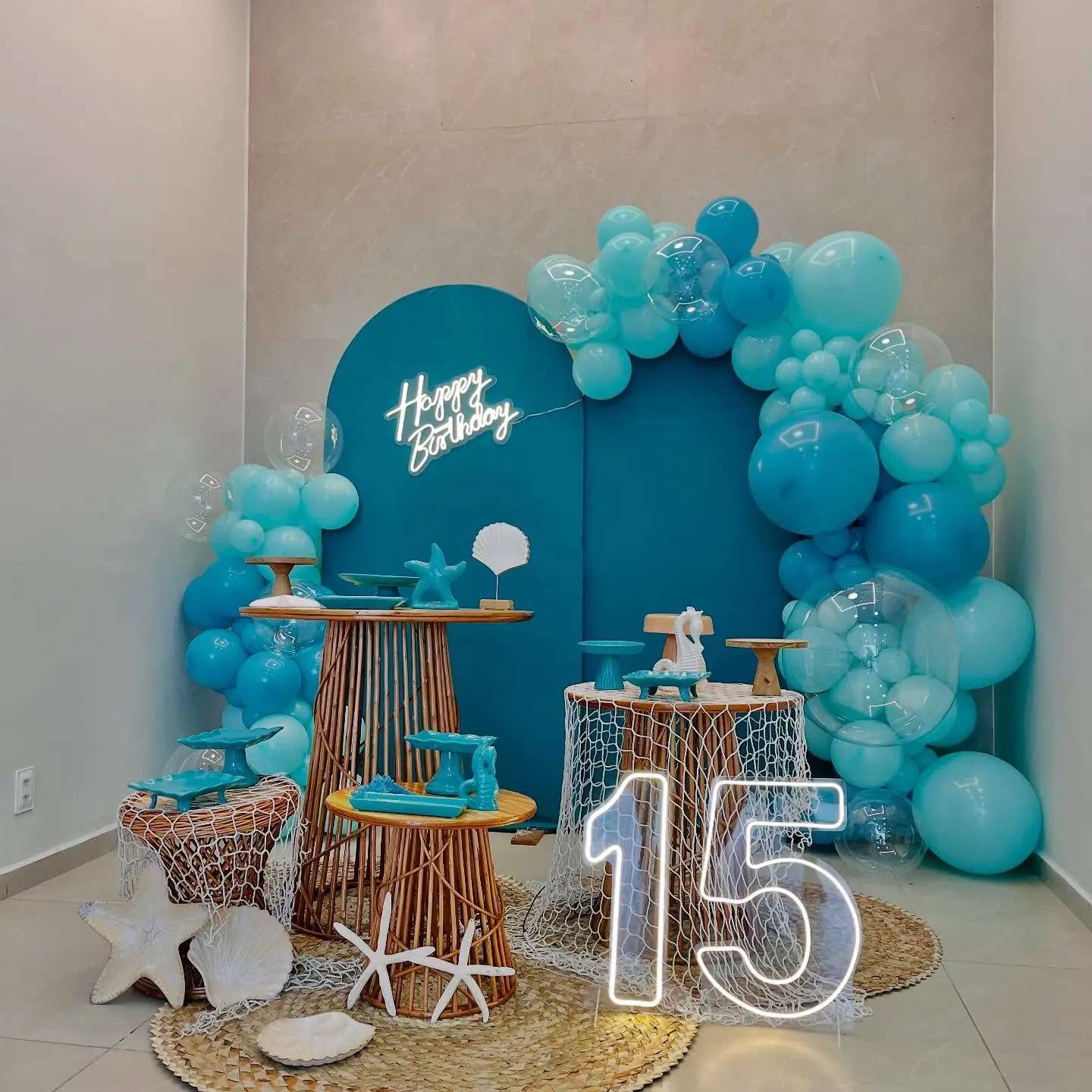 Decoração azul de aniversário com balões, mesa de doces e número 15 iluminado