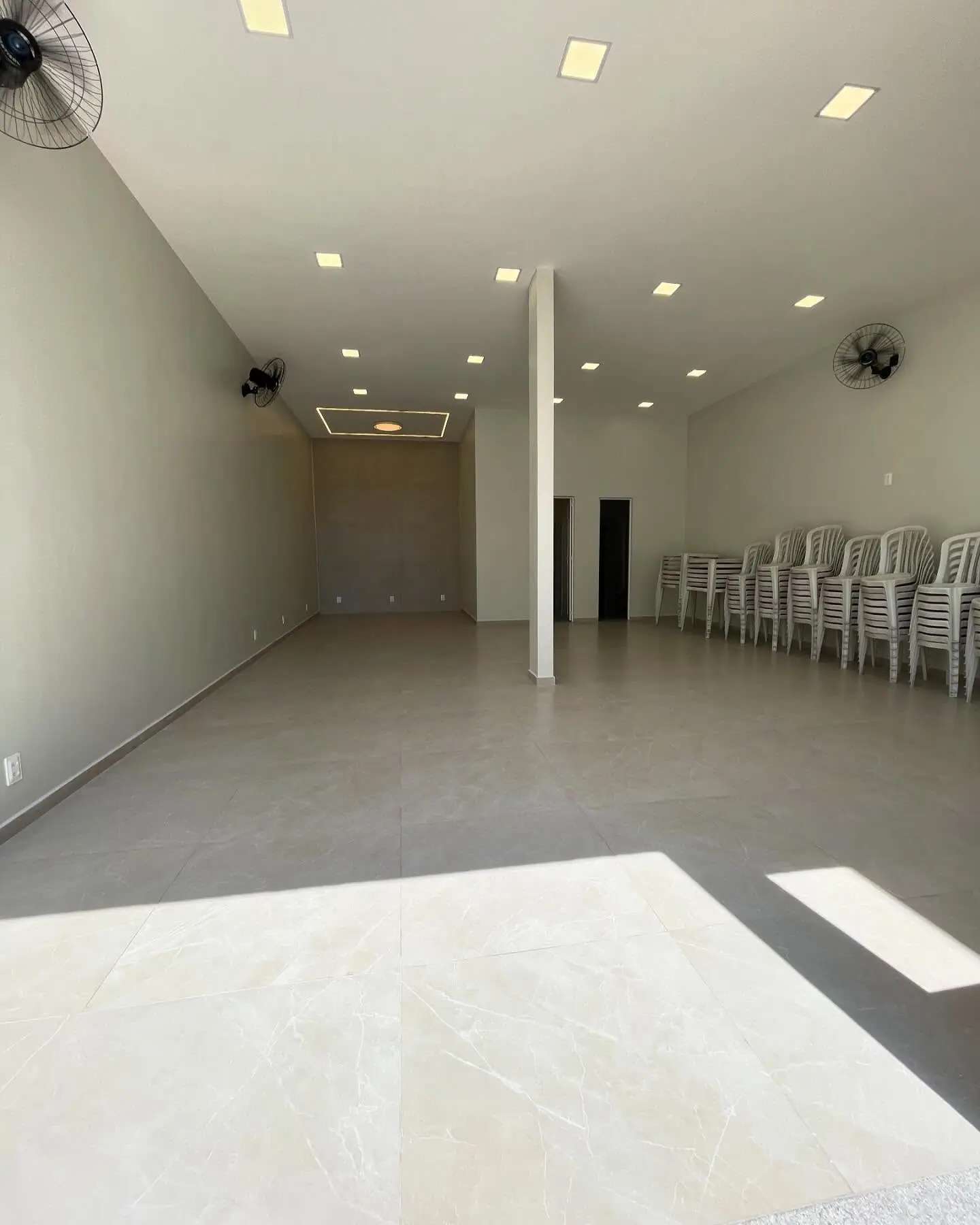 Salão interno do Cintra Club com piso claro, ventiladores e acesso à área externa