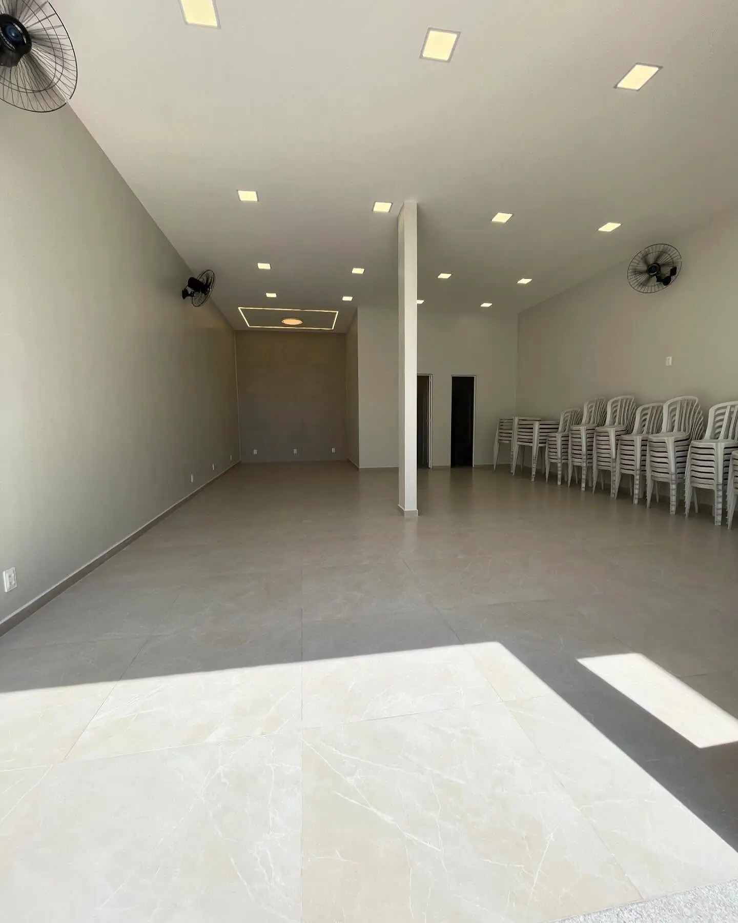 Salão interno do Cintra Club com piso claro, ventiladores e acesso à área externa